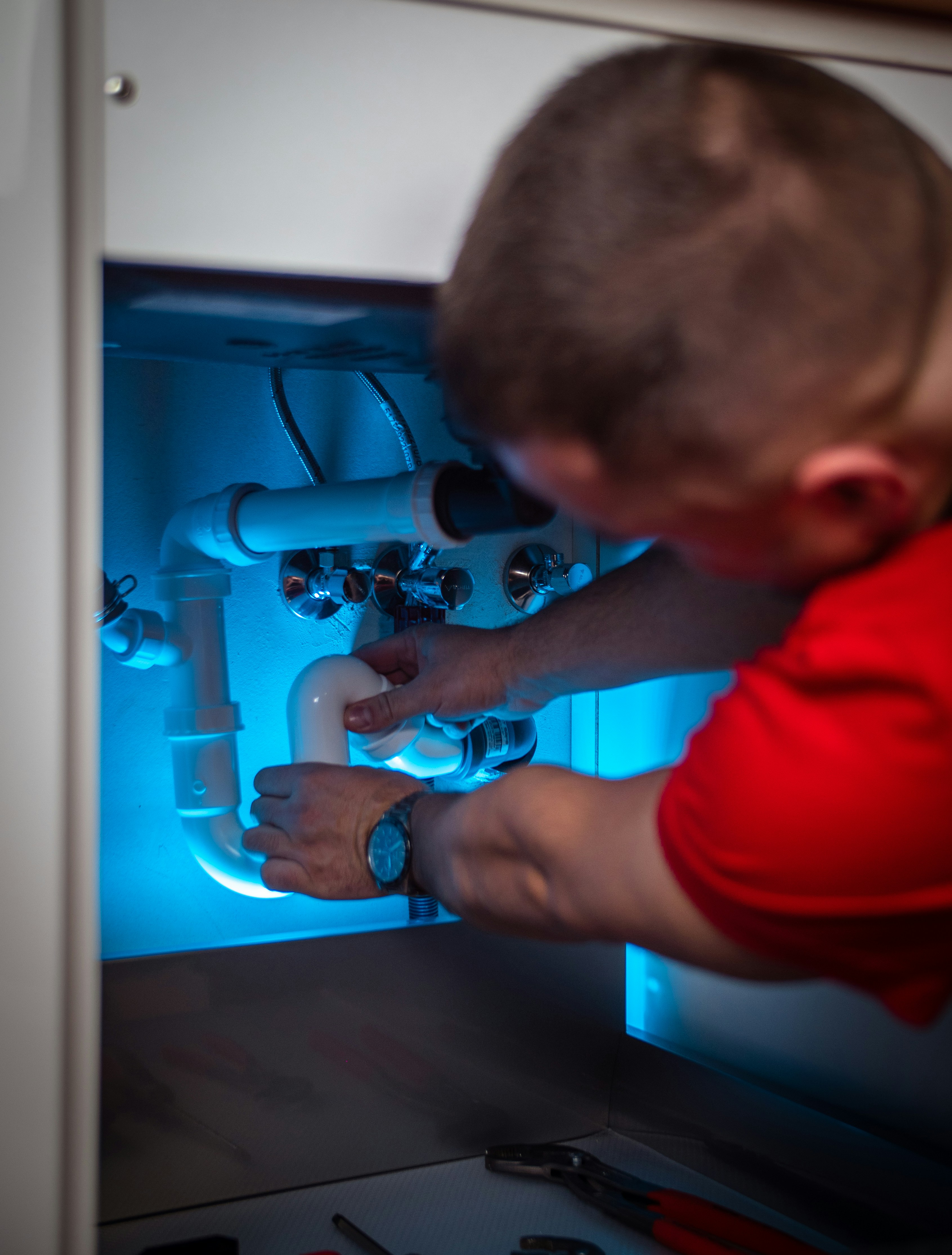 Minuteman Plumbing technician working under a kitchen sink